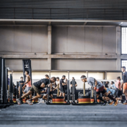 Atletas compitiendo en una prueba de empuje de trineo durante un evento de entrenamiento híbrido