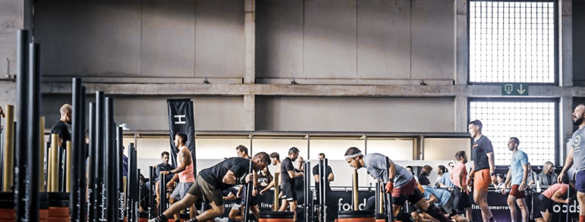 Atletas compitiendo en una prueba de empuje de trineo durante un evento de entrenamiento híbrido